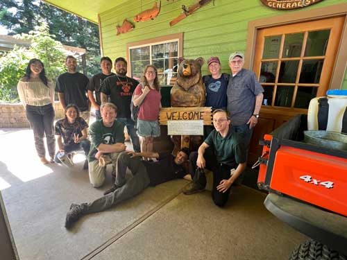 A group of volunteers posing beside a carved wooden bear